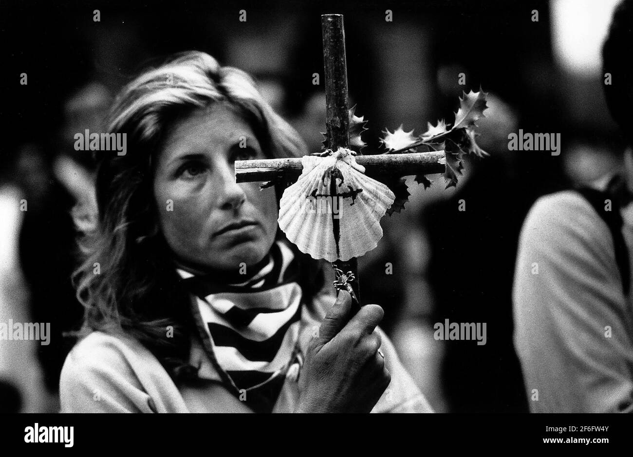 Santiago Pilgrim hält ein Holzkreuz mit einer daran befestigten Jakobsmuschel, ein traditionelles Zeichen eines Pilgers auf dem Jakobsweg in Spanien Stockfoto