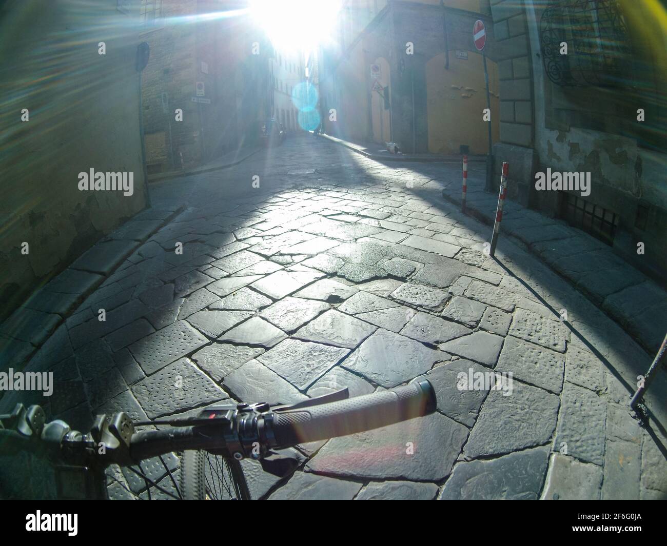 Reisen Sie mit dem Fahrrad durch die kopfsteingepflasterten Straßen der Altstadt von Florenz. Blick auf die erste Person mit strahlender Sonne vor dem Hotel. Action Cam-Ansicht Stockfoto