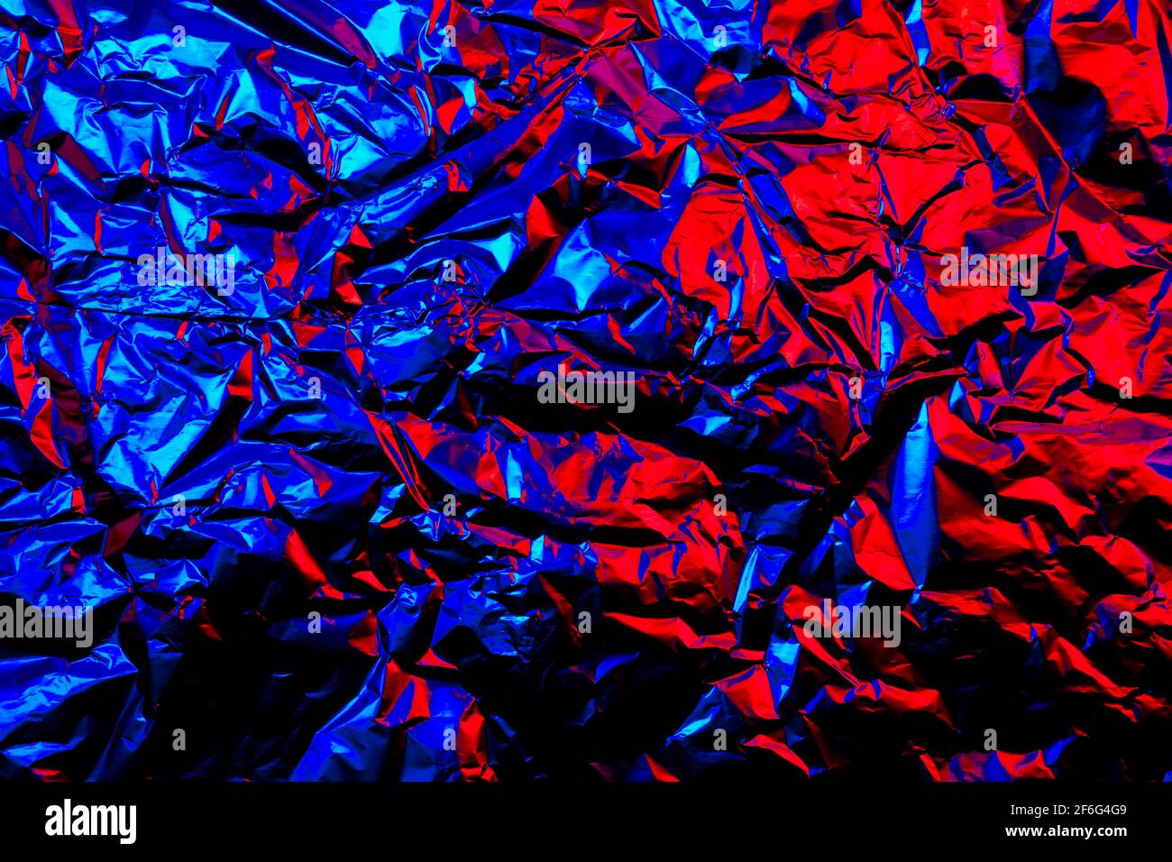Abstrakt rot und blau Aluminium zerknittert Folie Hintergrund Textur reflektierend Rotes und blaues Licht Stockfoto