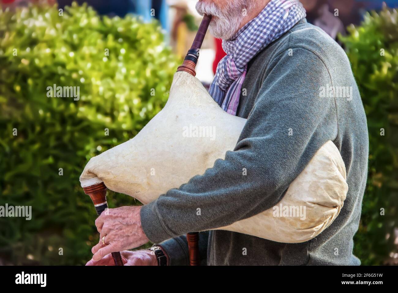 Älterer bärtiger Mann ist Pullover und Schal, der altes Schaffell spielt Dudelsack im Freien - abgeschnitten und selektiver Fokus Stockfoto