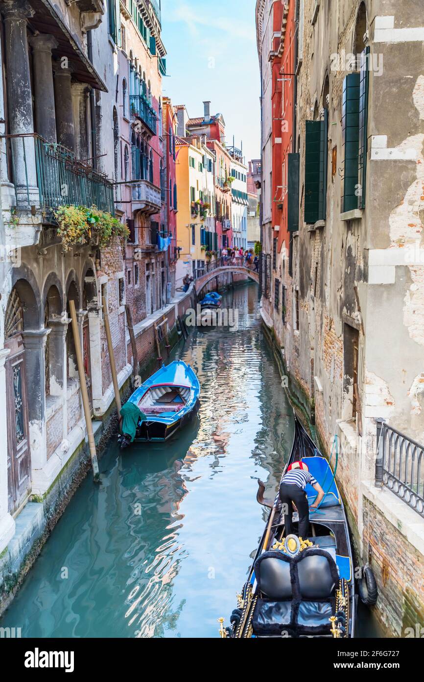 Italien. Das Stadtbild und die Architektur Venedigs. Stadtkanal und Boote darauf. Im Vordergrund Gondoliere, vertäute seine Gondel Stockfoto