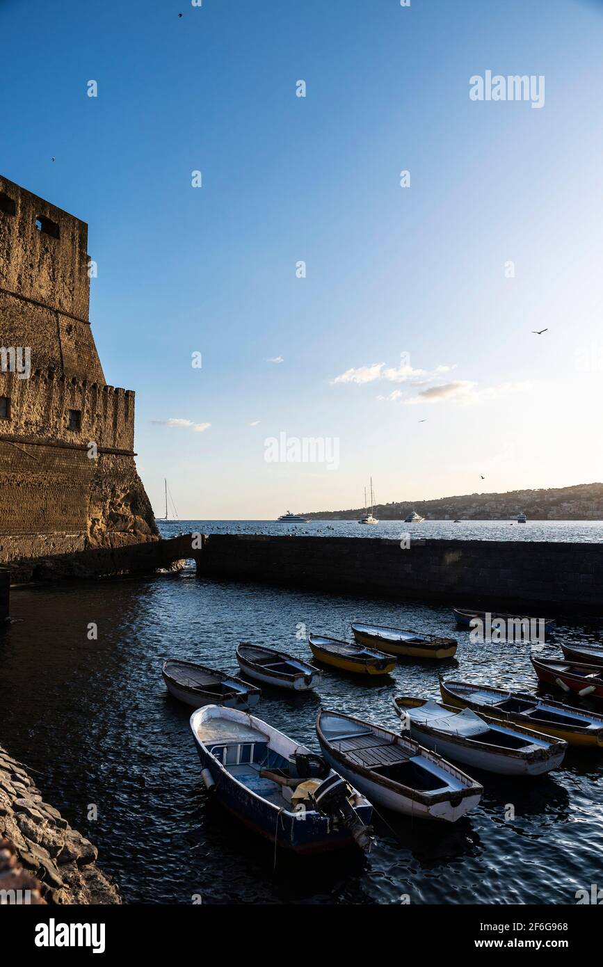 Fassade des Castel dell'Ovo (Egg Castle) und Boote, die auf einem Pier am Golf von Neapel, Italien, festgemacht sind Stockfoto