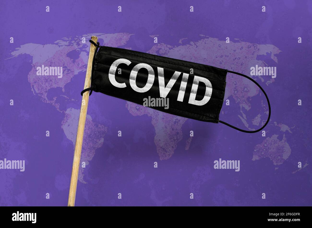 Die medizinische Maske fliegt schwarze Flagge auf dem Mast mit dem Text COVID. Schwarze Maske auf violettem, texturiertem Hintergrund der Weltkarte. Virenangriff-Flag. Konzept von coron Stockfoto