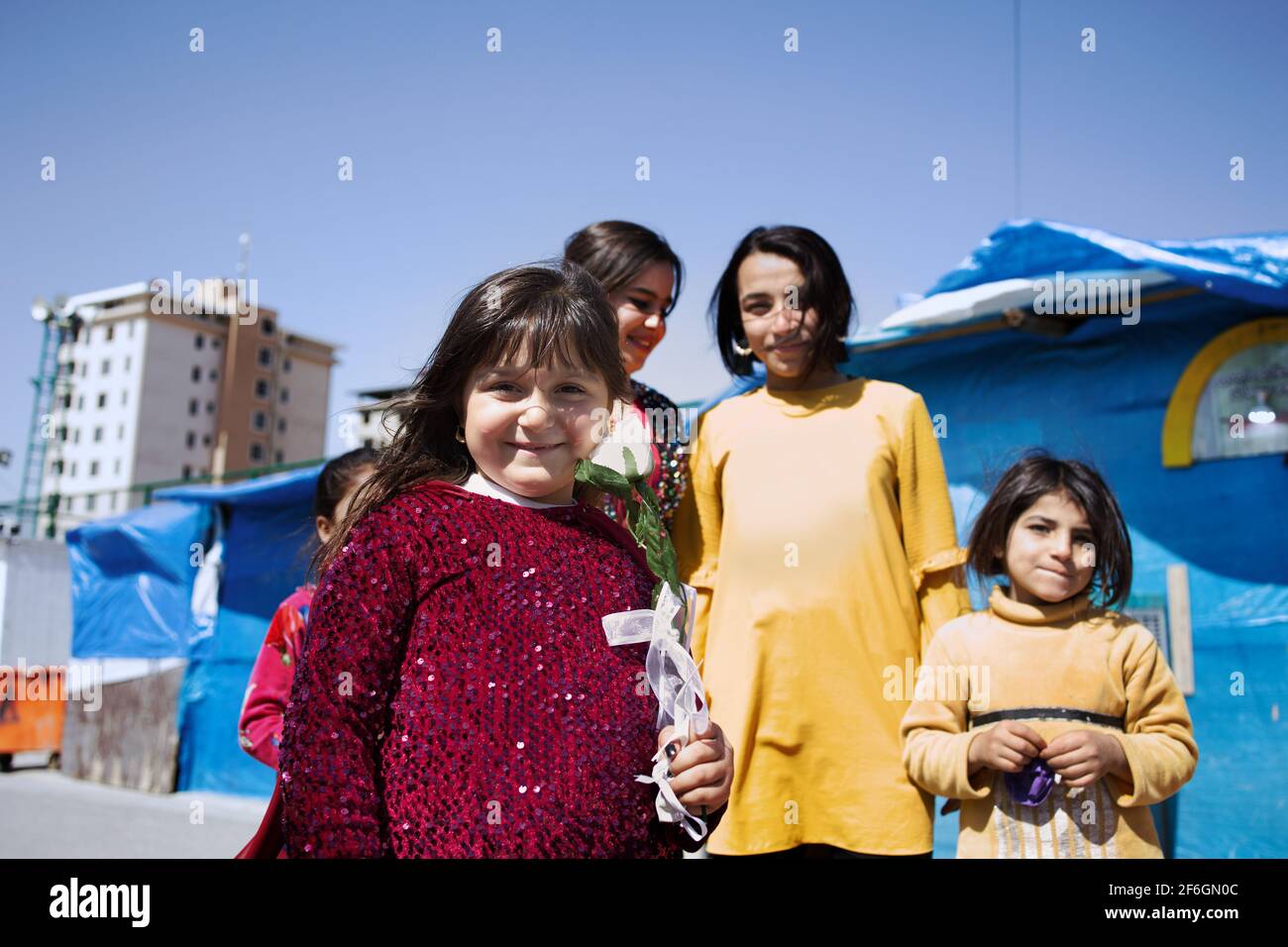 Erbil, Irak. Ein Mädchen mit einer weißen Rose in der Hand feiert den Internationalen Frauentag mit ihren Freunden im IDP-Camp Harshm. Kredit: MLBARIONA Stockfoto