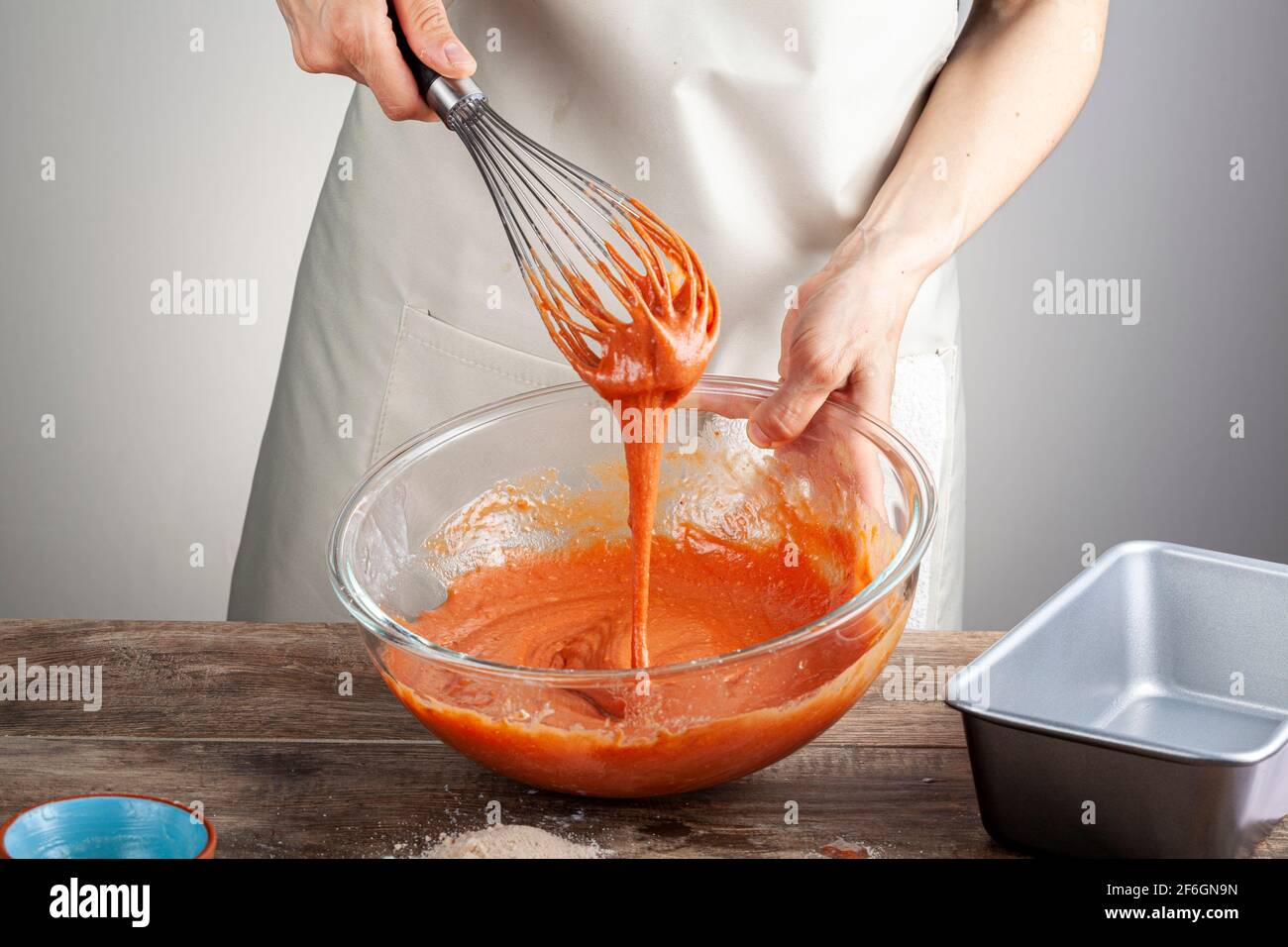 Eine Frau mischt einen blutroten Orangenkuchen in einer Glasschüssel mit einem Schneebesen im Ballon. Konzept für das Kochen, hausgemachte Rezept, Lebensmittelfarbe, Zusatzstoffe. Stockfoto