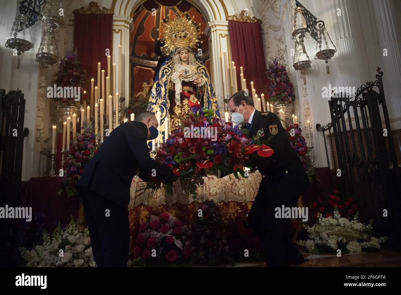 Malaga, Spanien. März 2021. Ein Mitglied der spanischen Nationalpolizei (R) wird gesehen, wie er der Jungfrau in der Kirche von Santiago einen Blumenstrauß als Teil der Verehrung während der Karwoche hinlegt.Trotz der Absage der Karwoche haben sich viele Bruderschaften entschieden, Messen zu organisieren, Verehrung und Ausstellung von Figuren von Christus und der Jungfrau heiraten mit in Kirchen nach allen Schutzmaßnahmen gegen Covid19. (Foto von Jesus Merida/SOPA Images/Sipa USA) Quelle: SIPA USA/Alamy Live News Stockfoto