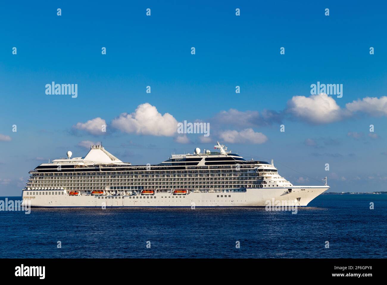 Großes, wunderschönes Luxuskreuzfahrtschiff am karibischen Meer, mit blauem Himmel und weißen Wolken im Hintergrund. Stockfoto