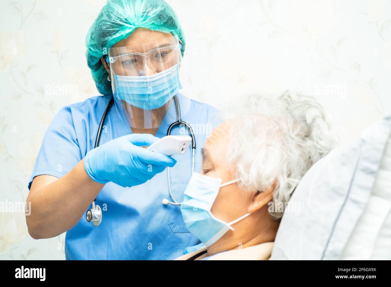 Arzt hält Digitalthermometer, um asiatische ältere oder ältere alte Dame Frau Patienten mit einer Gesichtsmaske messen haben ein Fieber im Krankenhaus, gesund st Stockfoto