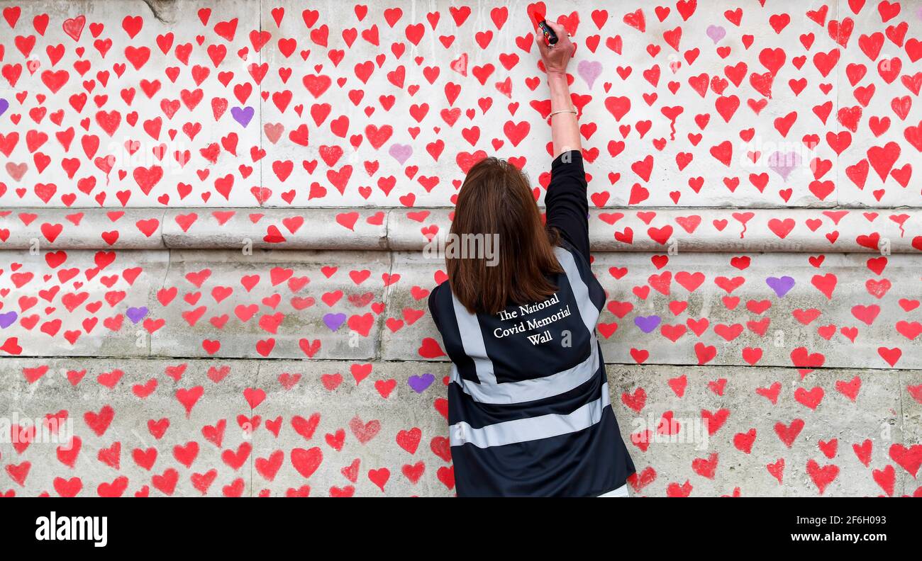 (210401) -- LONDON, 1. April 2021 (Xinhua) -- EIN Freiwilliger malt rote Herzen, die die Opfer darstellen, die am 19 31. März 2021 an der Nationalen COVID-Gedenkmauer vor dem St. Thomas' Hospital in London, Großbritannien, an der COVID gestorben sind. Trauerliche Familienmitglieder und Freiwillige sind dabei, Herzen entlang einer halben Meile Mauer gegenüber dem Houses of Parliament in London zu malen, um an diejenigen zu erinnern, die an COVID-19 gestorben sind. Weitere 4,052 Menschen in Großbritannien testeten COVID-19 positiv, was die Gesamtzahl der Coronavirus-Fälle im Land auf 4,345,788 brachte, so offizielle Zahlen von Wedne Stockfoto