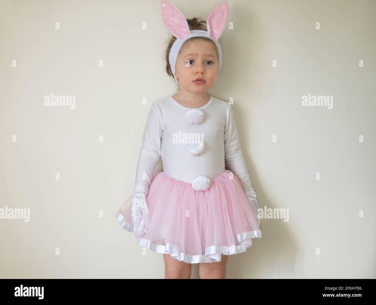 Selektiver Fokus. Hübsches kleines Mädchen in einem Osterhasen Kostüm steht aufgeregt vor der Wand. Stockfoto