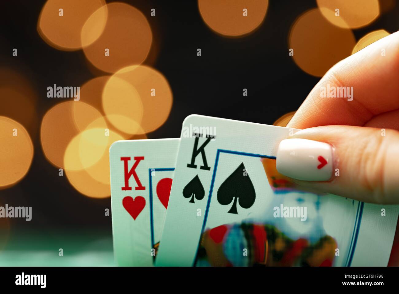 Weibliche Hand hält Spielkarten gegen Bokeh Hintergrund Stockfoto