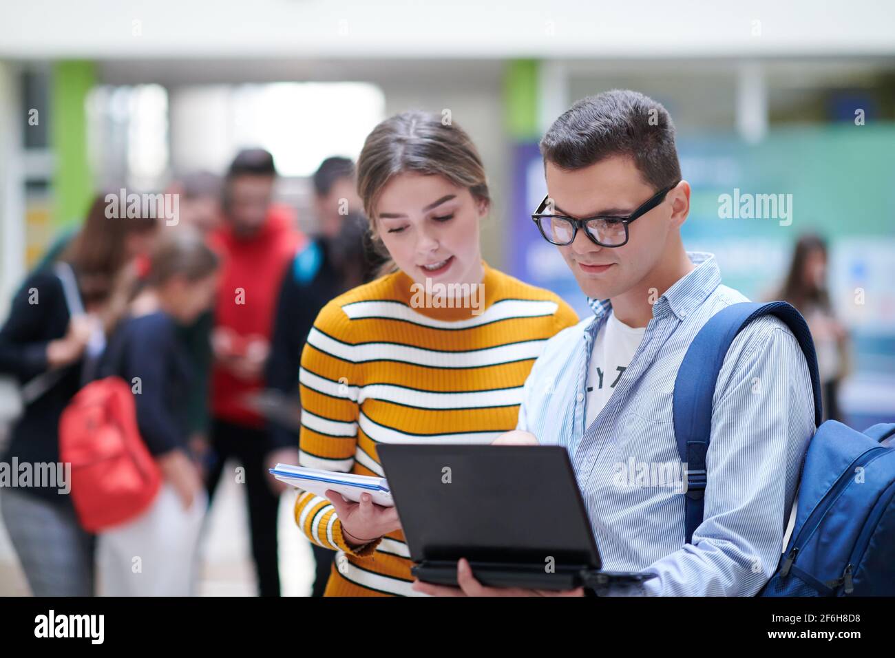 Zwei Studenten mit moderner Technik stehen dabei im Flur Warten auf den Beginn des Unterrichts Stockfoto