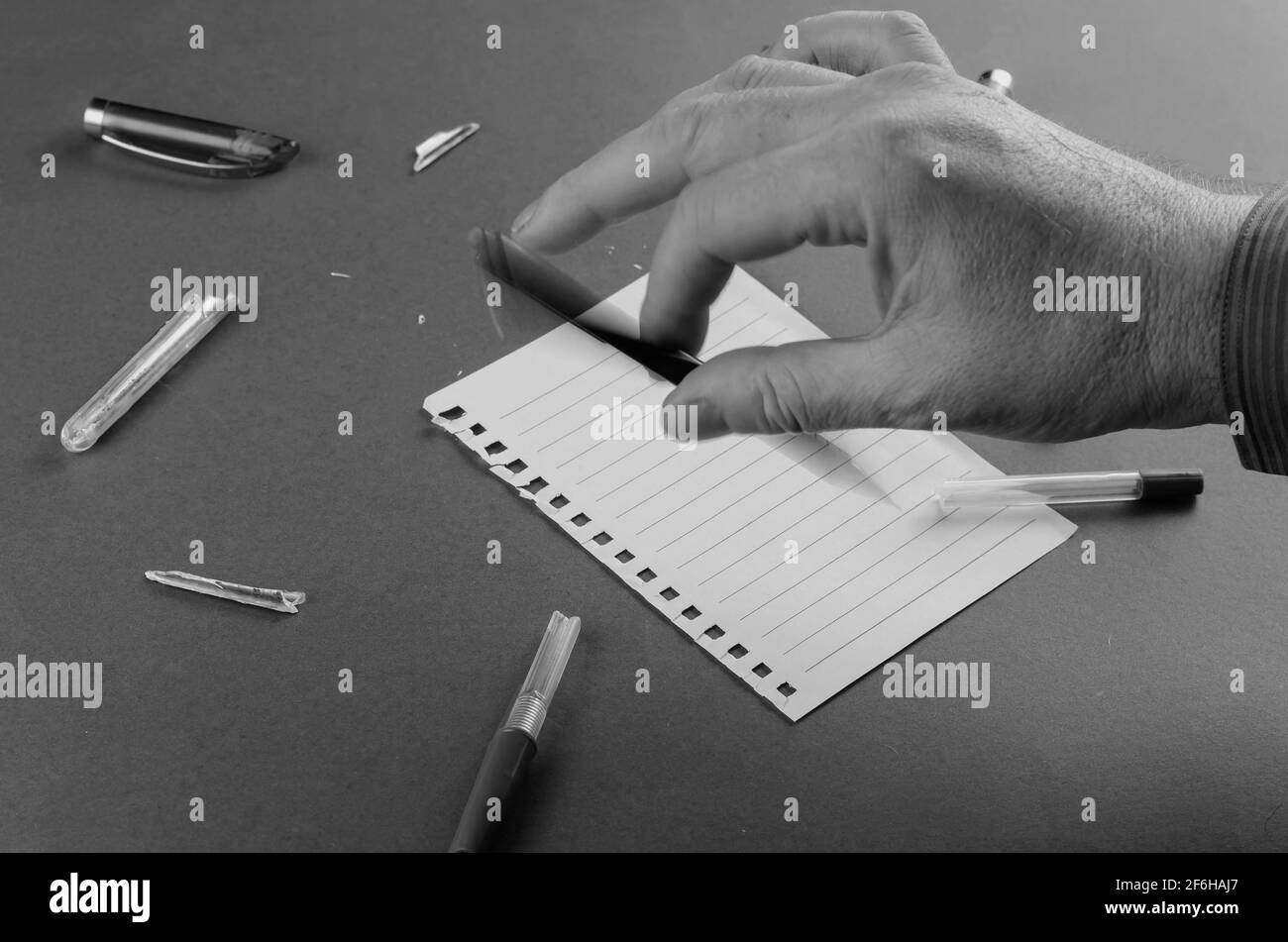 Bewegungsunschärfe. Der Erwachsene Mann spielt nervös mit dem Stift über dem Schreibtisch. Defekte Stifte und leeres Blatt Papier auf der Rückseite. Konzept der Geschäftsprobleme, Konflikt wi Stockfoto