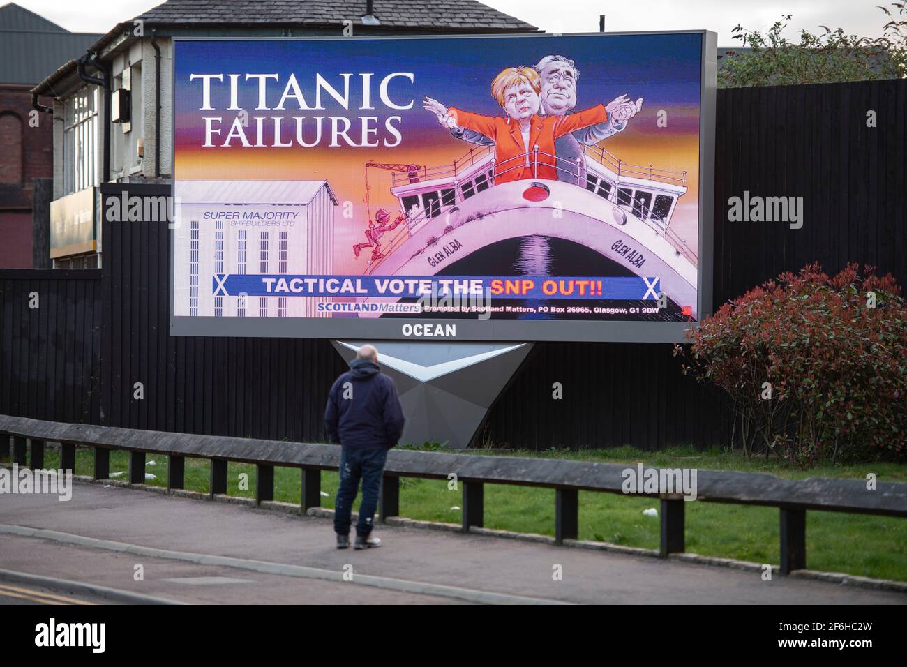Glasgow, Schottland, Großbritannien. April 2021. IM BILD: Eine riesige elektronische Plakatwand, auf der eine Grafik mit dem Titel „TITANIC FAILURES“ und „TACTICAL VOTEE THE SNP OUT“ abgebildet ist, mit Comic-Figuren von Nicola Sturgeon und Alex Salmond, die die berühmte Szene aus dem Titanic am Bug nachspielen, aber stattdessen auf der Fähre von Glen Alba. Pressemitteilung Link: https://www.scotlandmatters.co.uk/titanicfailurebillboard/ Artikel Link: https://www.bbc.co.uk/news/amp/uk-scotland-glasgow-west-56579158?  twitter impression=true&s=03 Quelle: Colin Fisher/Alamy Live News Stockfoto