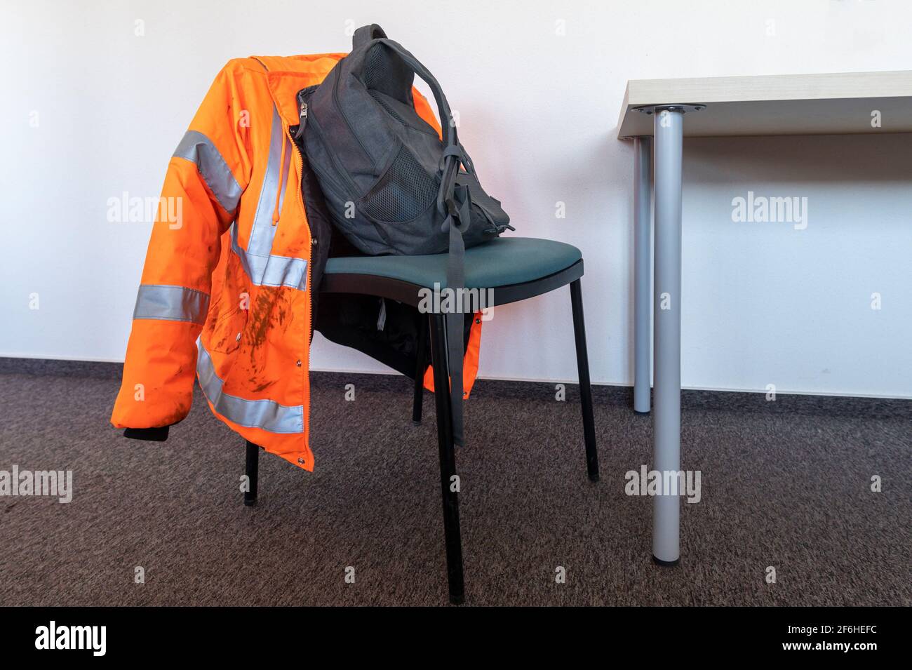 Sicherheitsjacke und Rucksack auf einem Stuhl Stockfoto