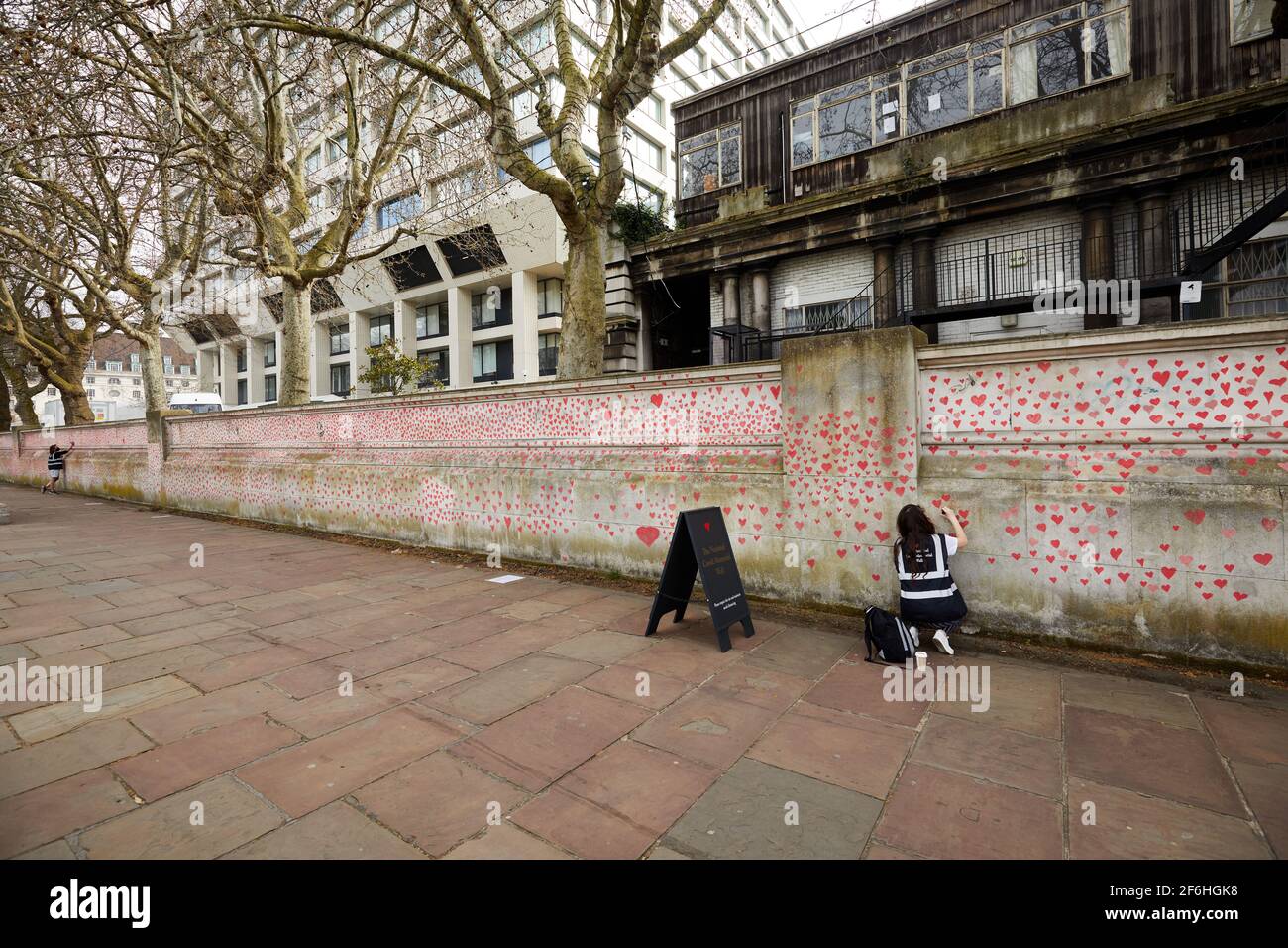 London, Großbritannien - 31. März 2021: Familie und Freunde von Covid-19-Opfern malen rote Herzen an der National Covid Memorial Wall vor dem St. Thomas' Hospital im Zentrum von London. Jedes einzeln gezeichnete Herz stellt ein Opfer des Coronavirus dar. Stockfoto