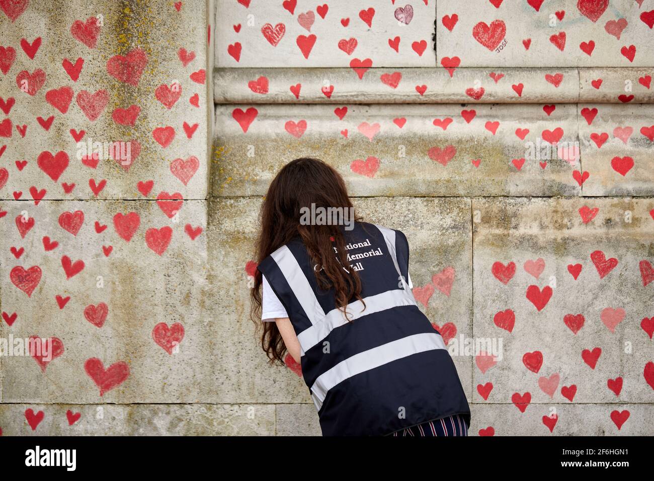 London, Großbritannien - 31. März 2021: Familie und Freunde von Covid-19-Opfern malen rote Herzen an der National Covid Memorial Wall vor dem St. Thomas' Hospital im Zentrum von London. Jedes einzeln gezeichnete Herz stellt ein Opfer des Coronavirus dar. Stockfoto