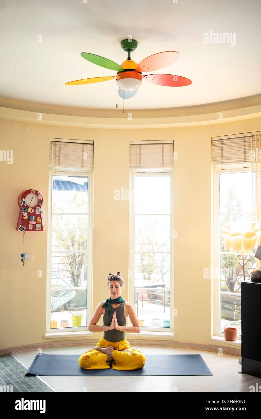 Junge Frau meditiert in Lotusposition in ihrer gemütlichen Wohnung Während ihres Yoga-Unterrichts zu Hause Stockfoto