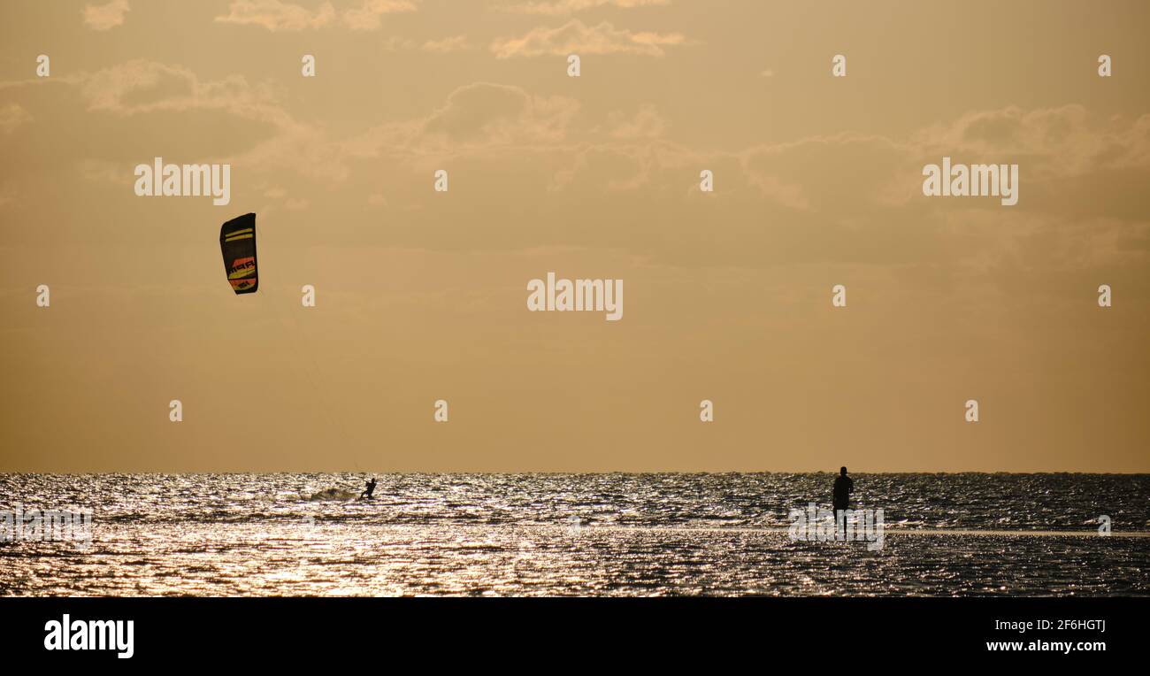 Ein Kitesurfer, der an einem Strand in der mexikanischen Karibik trainiert, eine Person, die vor dem Licht steht und ihn beobachtet Stockfoto