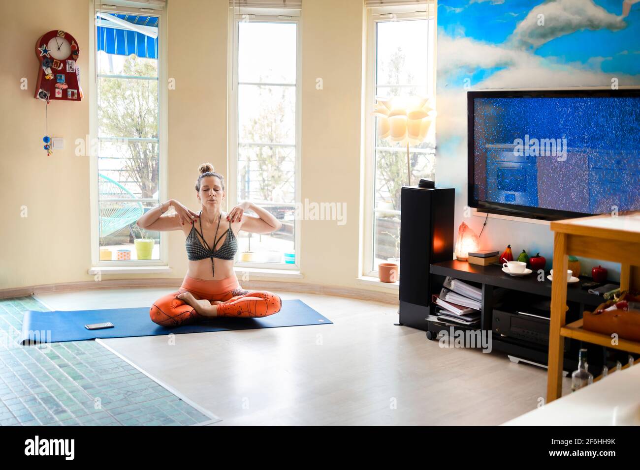 Junge Frau meditiert in Lotusposition in ihrer gemütlichen Wohnung Während ihres Yoga-Unterrichts zu Hause Stockfoto