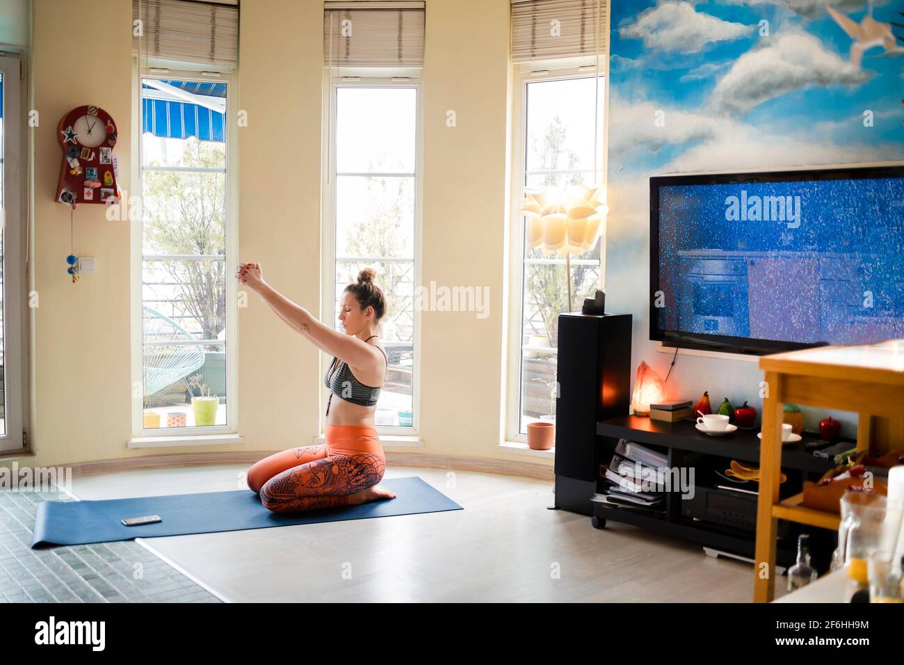 Schöne Frau streckt ihre Arme, während sie Yoga macht Gemütliche Wohnung Stockfoto