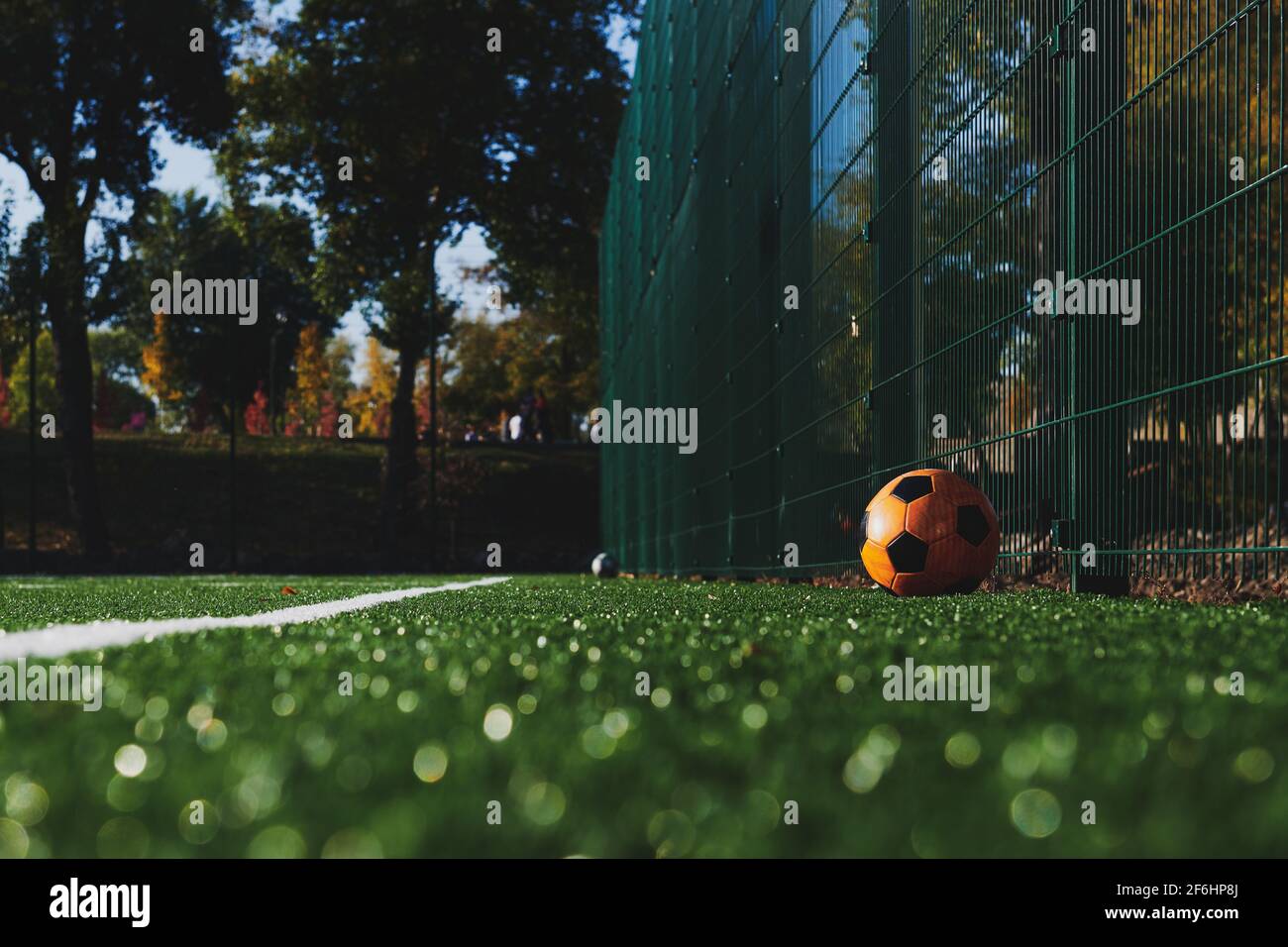 Künstliches leeres Fußballfeld mit einer orangefarbenen Kugel. Geringe Schärfentiefe. Weiße Linie und Kopierbereich. Horizontales Foto. Vintage-Tonung. Stockfoto