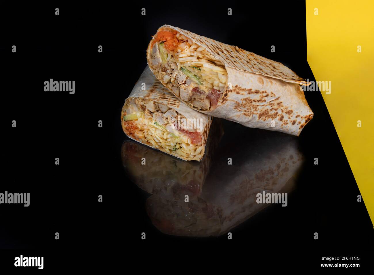 Hühnerrolle mit Gemüse. Frischer Kohl, Gurken, Karotten und Kräuter. Vor einem dunklen Hintergrund. Shawarma. Speicherplatz kopieren. Stockfoto