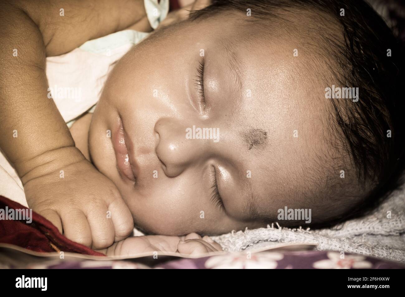 Nahaufnahme eines niedlichen schlafenden Neugeborenen. Nahaufnahme Porträt eines süßen gerade geborenen Jungen gefangen in schläfriger Stimmung schläfrige Augen. Hand auf Chin. Fro Stockfoto