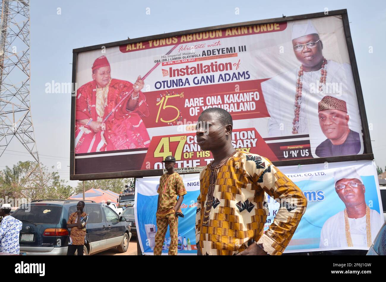 Ein Mann, der vor einer Plakatwand steht und Otuba Gani Adams als 15. Ankündigt, sind Ona Kankanfo aus Yoruba Land von Alaafin aus Oyo, Bundesstaat Oyo, Nigeria. Stockfoto