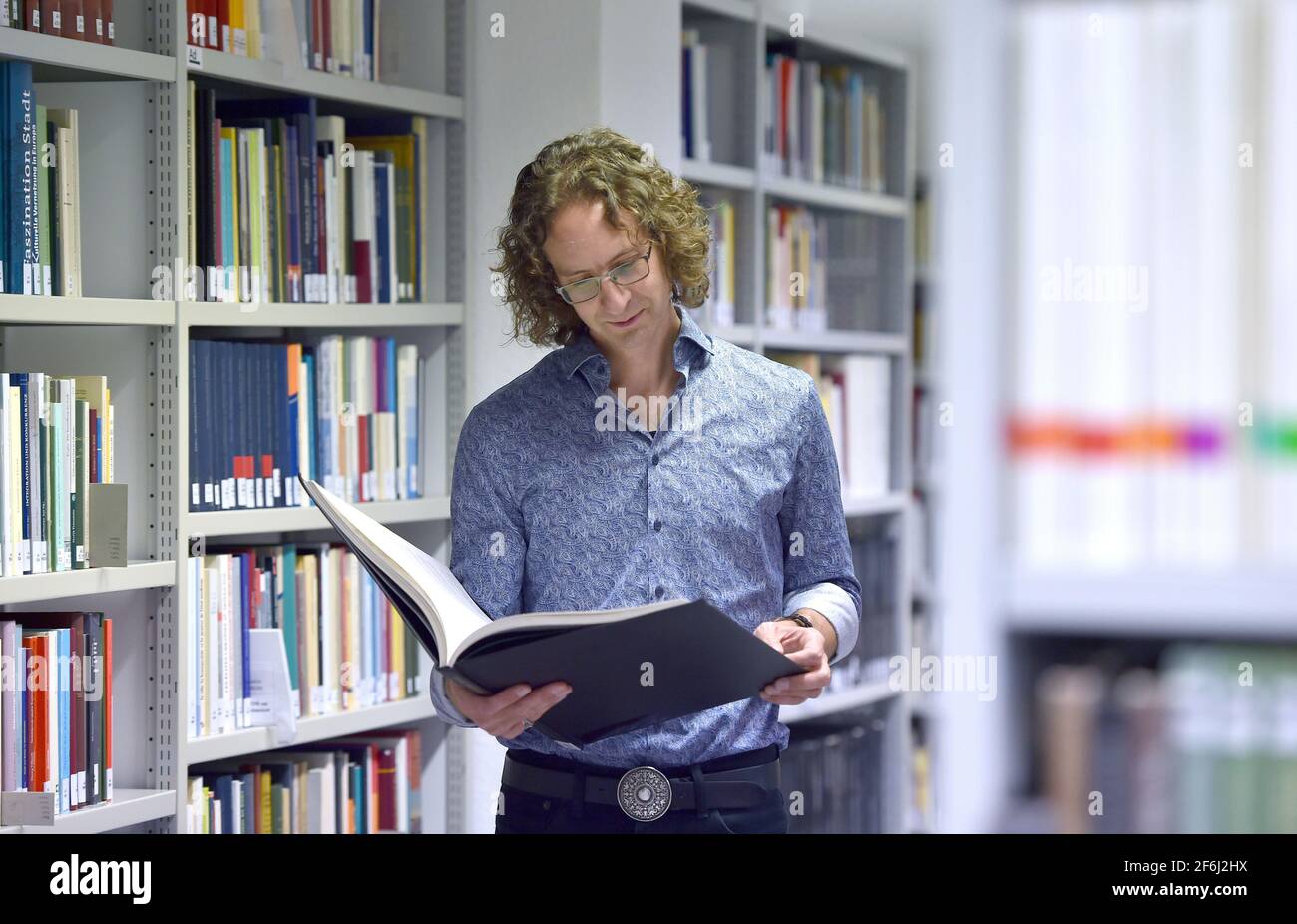 17. September 2020, Nordrhein-Westfalen, Münster: Daniel Stracke, Historiker am Institut für vergleichende Stadtgeschichte der Universität Münster, schaut sich ein altes Buch an. Der Historiker hat einen Wandteppich aus der Renaissance aus der Gemeinde Peronne entdeckt und seine Geschichte rekonstruiert. Foto: Caroline Seidel/dpa Stockfoto