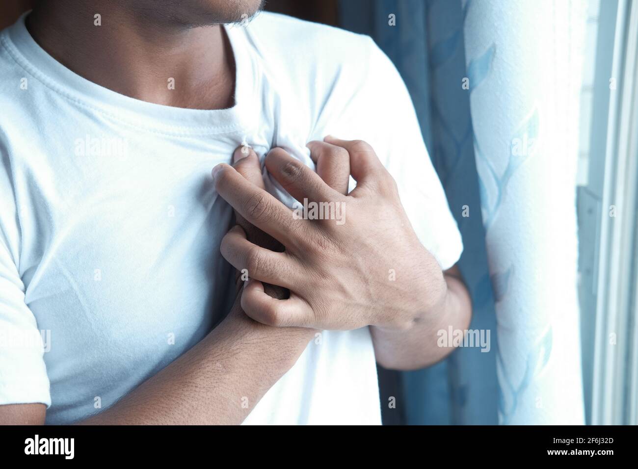 Junger Mann leidet Schmerzen im Herzen und hält Brust mit Hand Stockfoto