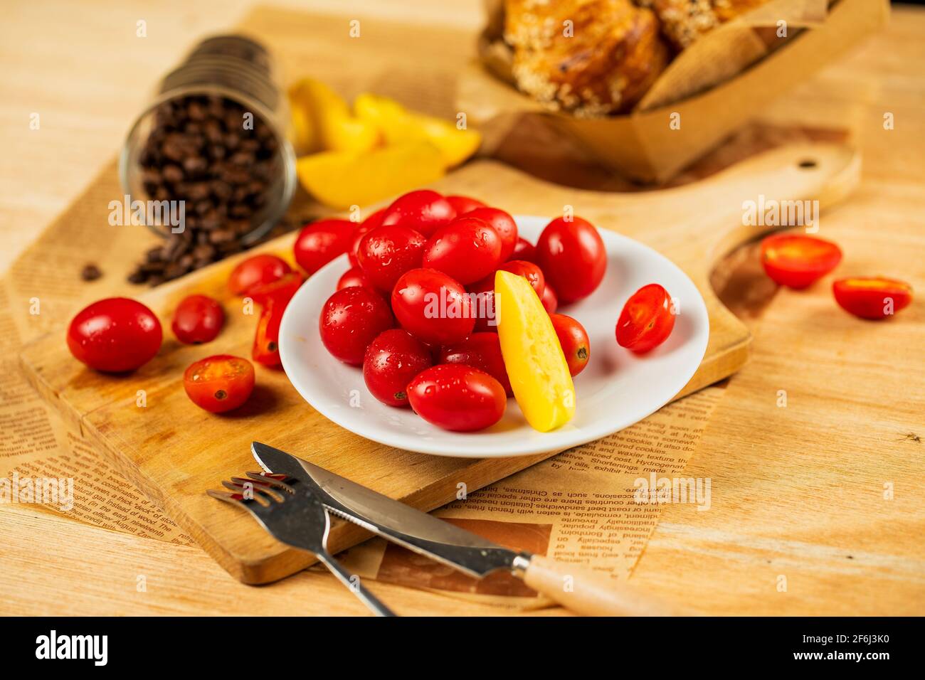 Rote reife Tomaten auf Holztisch verstreut. Holzhintergrund mit Kirschtomaten, Zitrone und Kaffeebohne Stockfoto