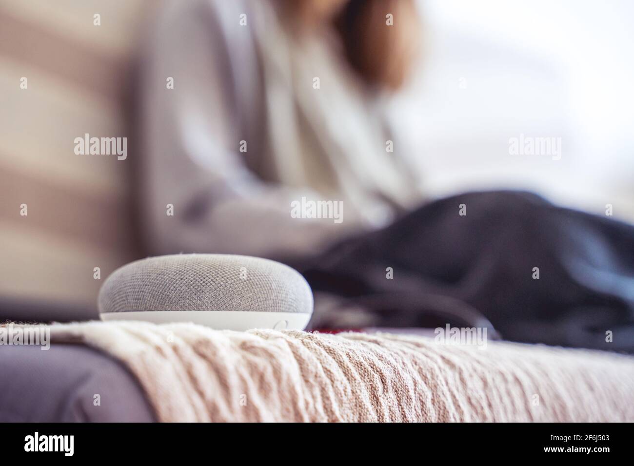 Sprachgesteuerter intelligenter AI-Lautsprecher. Frau, die im Hintergrund arbeitet Stockfoto