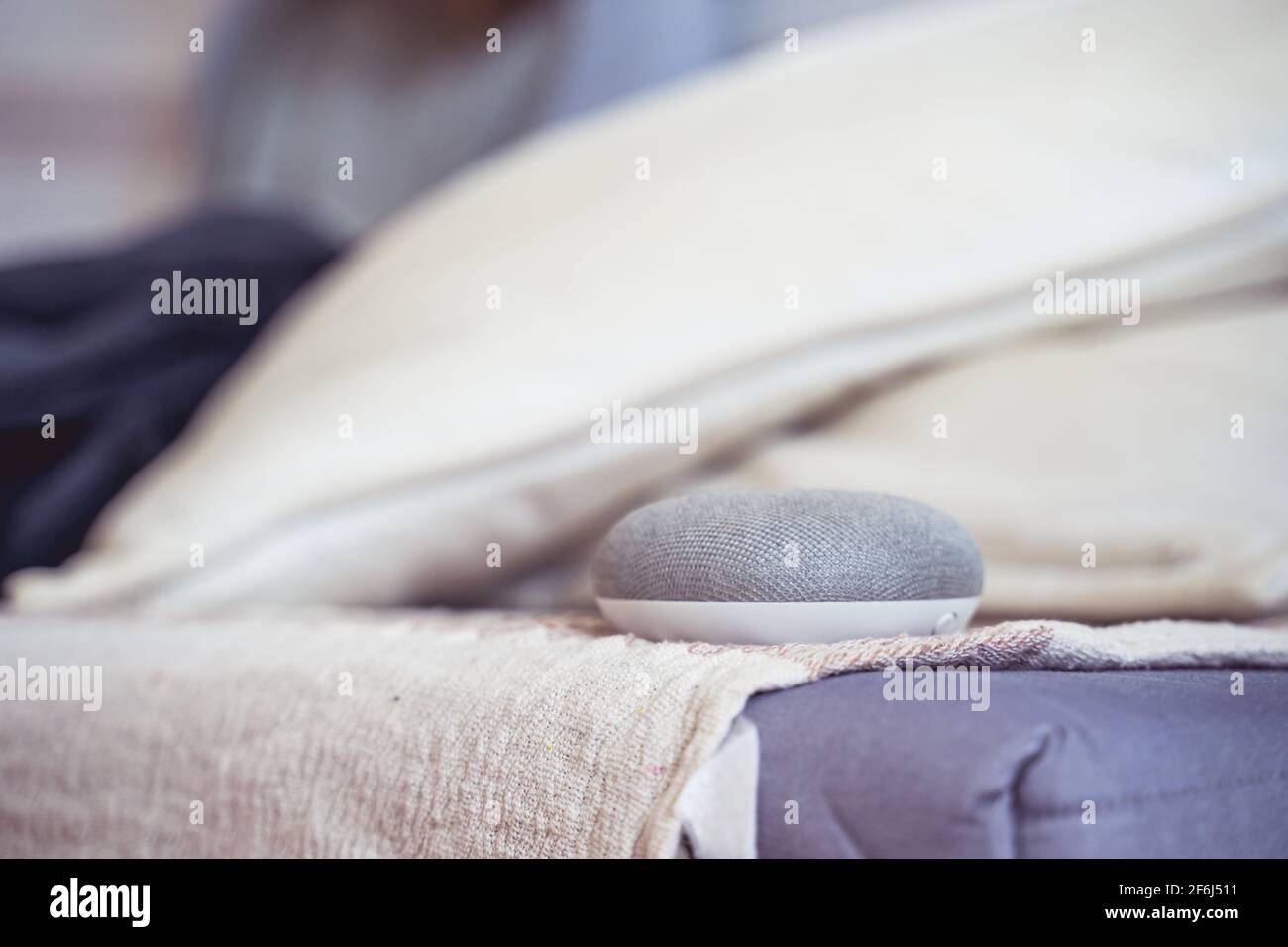 Sprachgesteuerter intelligenter AI-Lautsprecher. Frau, die im Hintergrund arbeitet Stockfoto