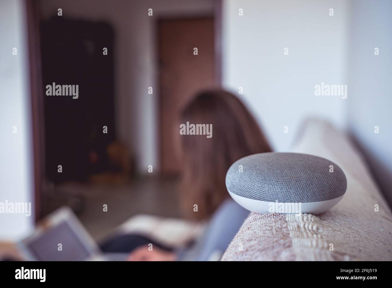 Sprachgesteuerter intelligenter AI-Lautsprecher. Frau, die im Hintergrund arbeitet Stockfoto