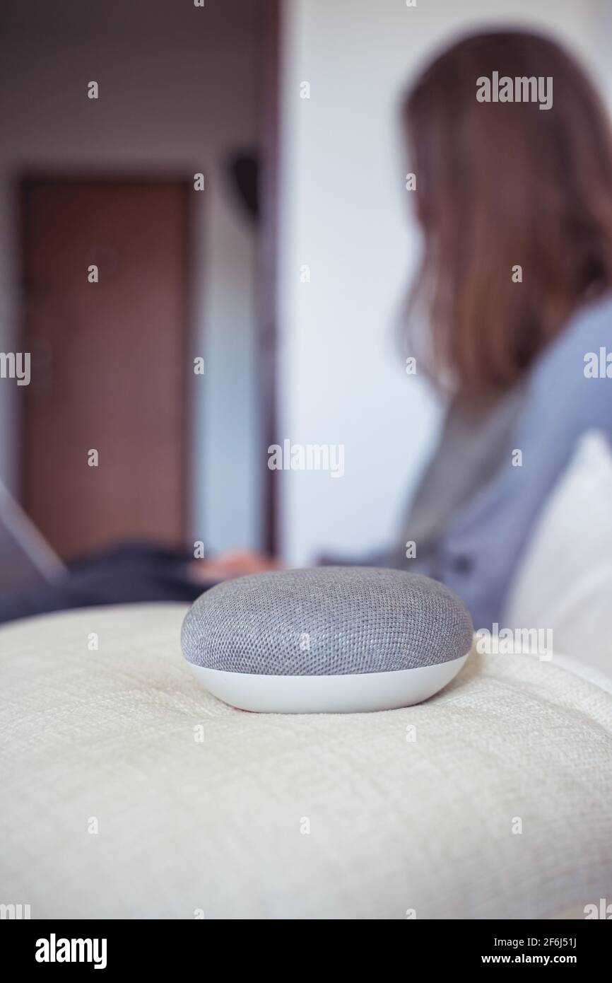 Sprachgesteuerter intelligenter AI-Lautsprecher. Frau, die im Hintergrund arbeitet Stockfoto