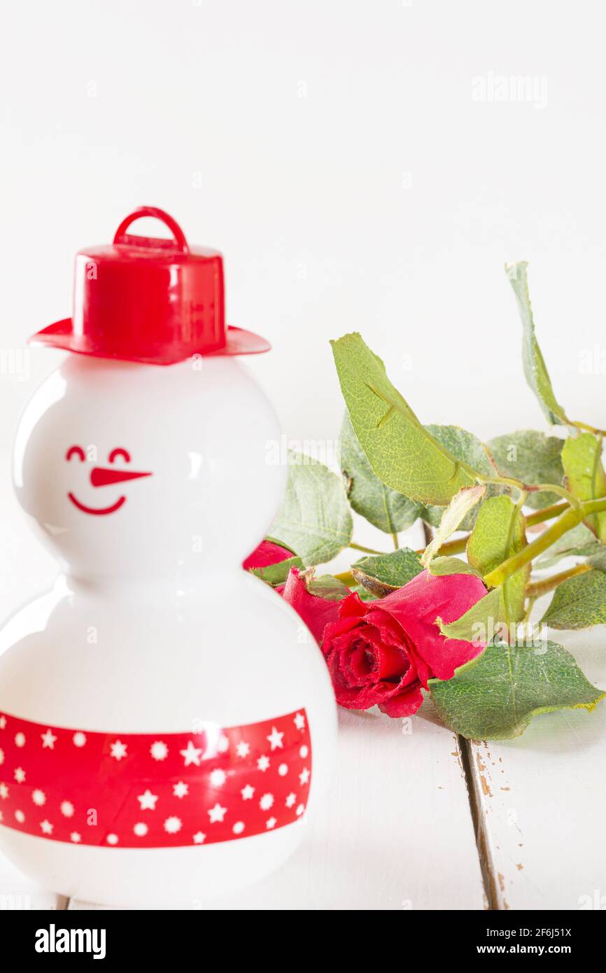 Shampoo-Flasche mit einigen roten Rosen im Hintergrund. Es ist ein Produktfoto, vertikale Aufnahme und wo die Farbe Weiß vorherrscht. Stockfoto