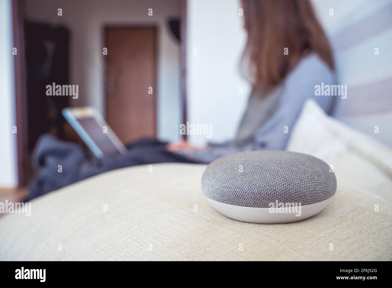 Sprachgesteuerter intelligenter AI-Lautsprecher. Frau, die im Hintergrund arbeitet Stockfoto