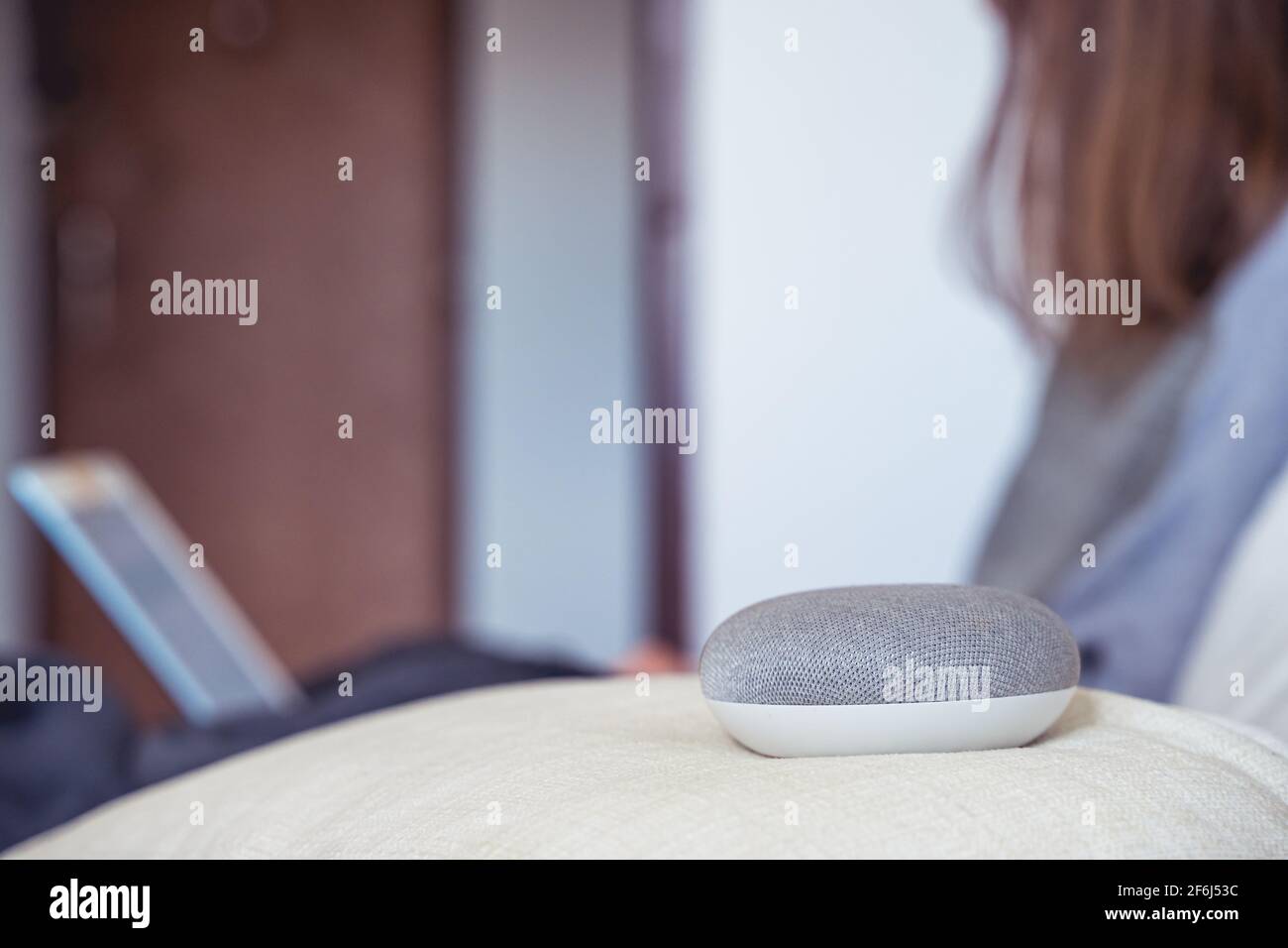 Sprachgesteuerter intelligenter AI-Lautsprecher. Frau, die im Hintergrund arbeitet Stockfoto