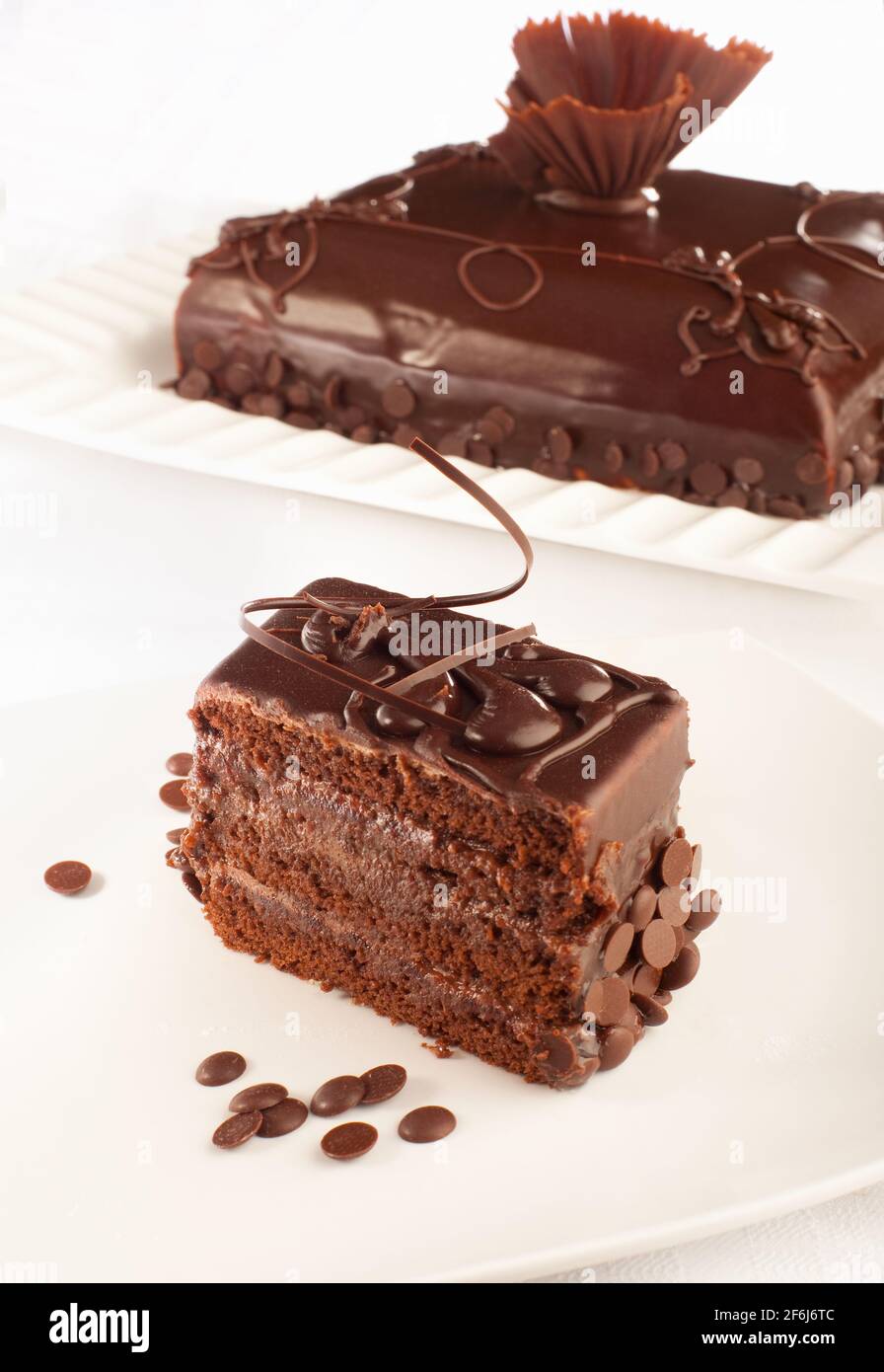 Ein stilvoller Schokoladenkuchen und ein Stück davon davor. Stockfoto