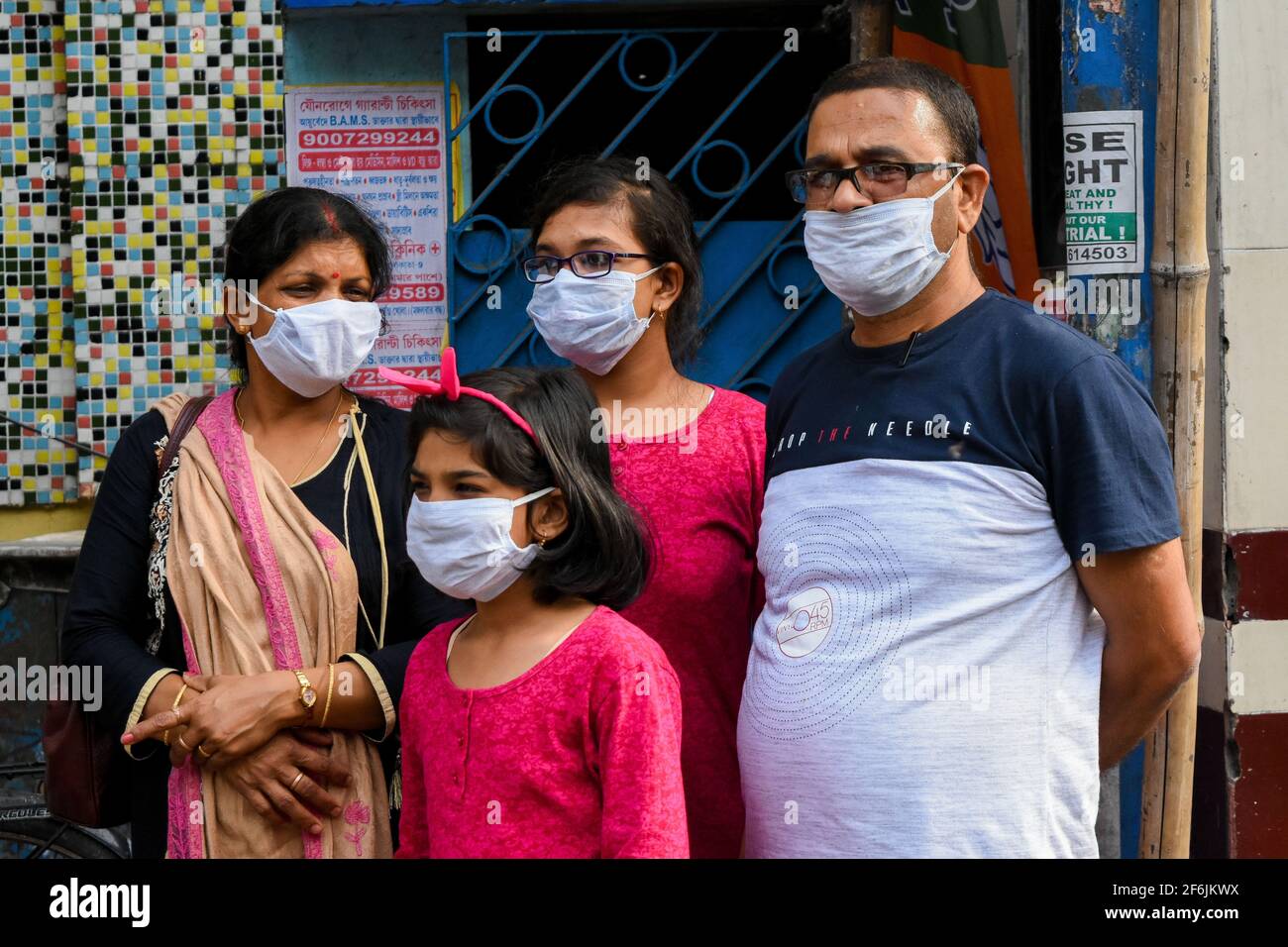 Eine Familie mit Schutzmaske wartet auf einen Bus an einem Terminal in Kalkutta, Indien. Stockfoto