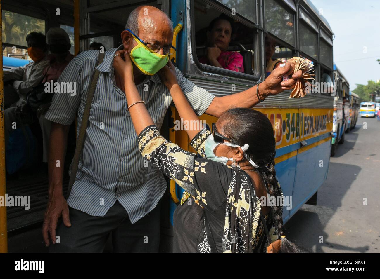 Ein anders sabled girl, das auf einer Straße in Kalkutta, Indien, eine Schutzmaske an Busfahrer und Helfer verteilt. Stockfoto