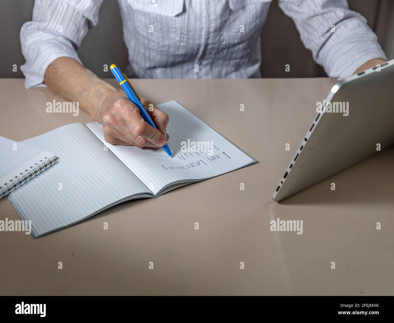 Notebook, Hand mit Griff, Tablet auf Lichttisch. Online-Englischschulung. Stockfoto