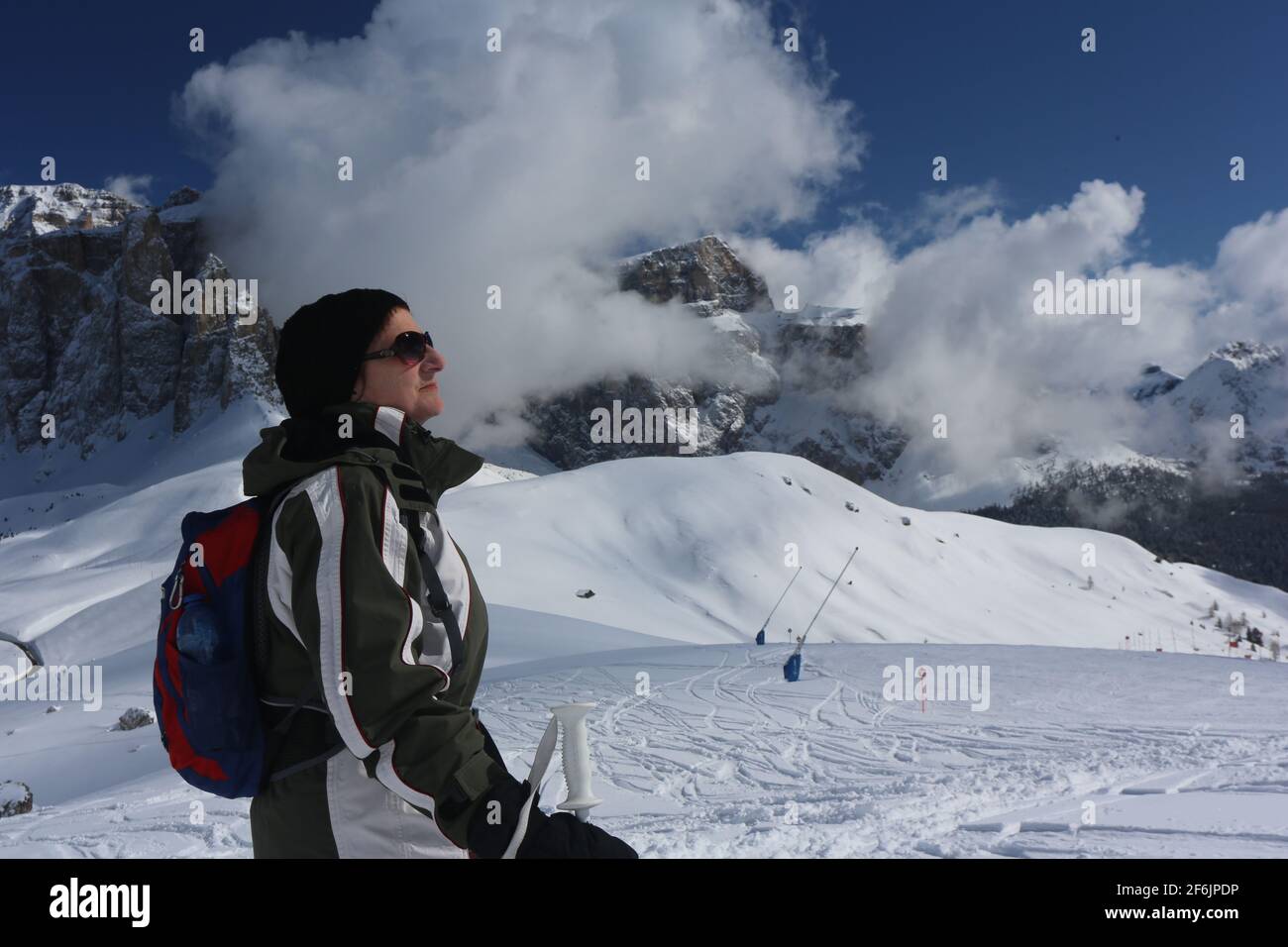 Schöne Frau beobachtet vom Langkofel die schneebedeckten Berge und Felsen am winterlichen Sella Joch in Südtirol in den Dolomiten Stockfoto