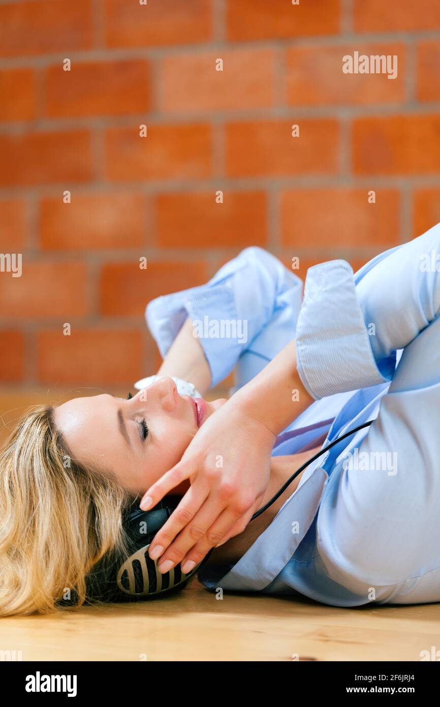 Geschäftsfrau, die zu Hause Musik oder einen Sprachkurs hört Entspannt auf dem Boden liegen Stockfoto