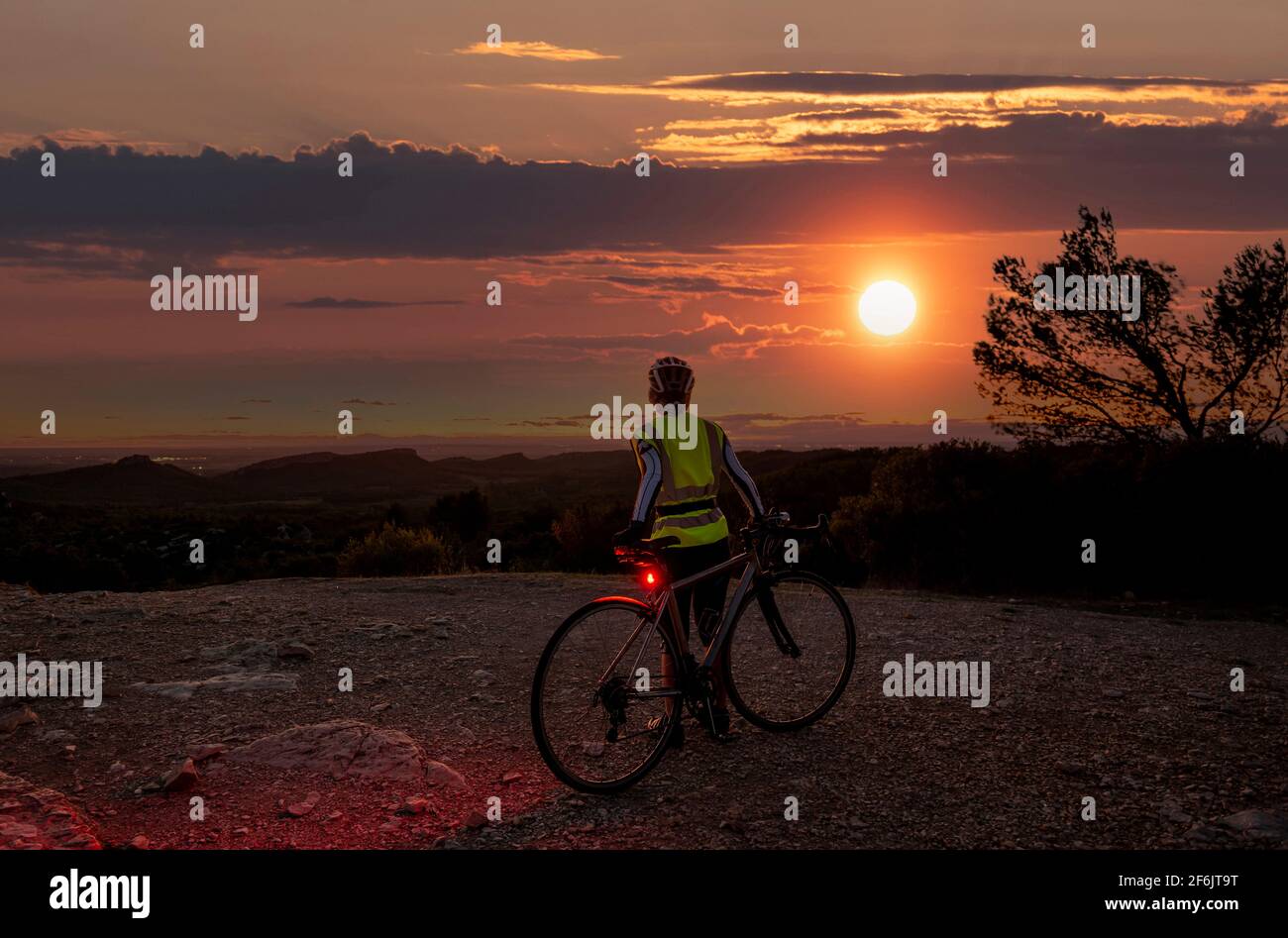 Reife weibliche Radfahrer bei Sonnenuntergang auf dem Gipfel des Alpilles, in der Nähe von San Remy, Provence, Frankreich. Stockfoto