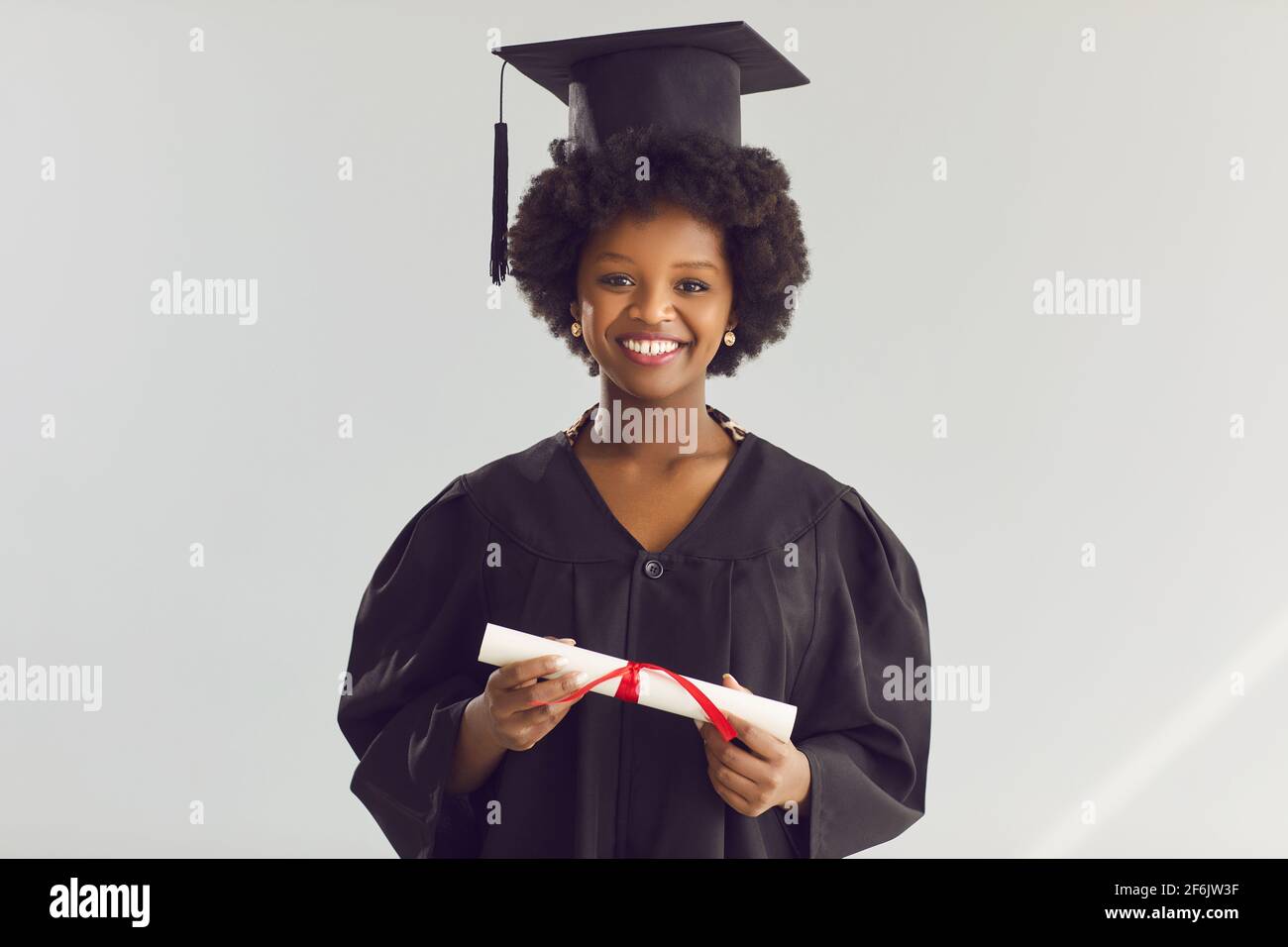 afroamerikanische Frau in akademischem Hut und Kleid mit Diplom headshot aus dem studio Stockfoto