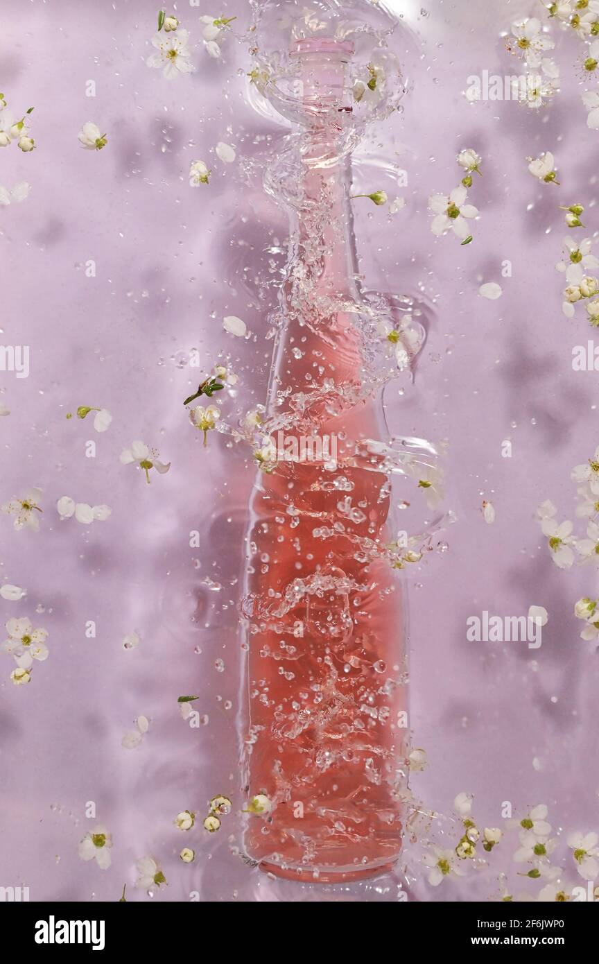 Spritzer Flasche rosa Rosenwein und Frühlingsblumen Stockfoto