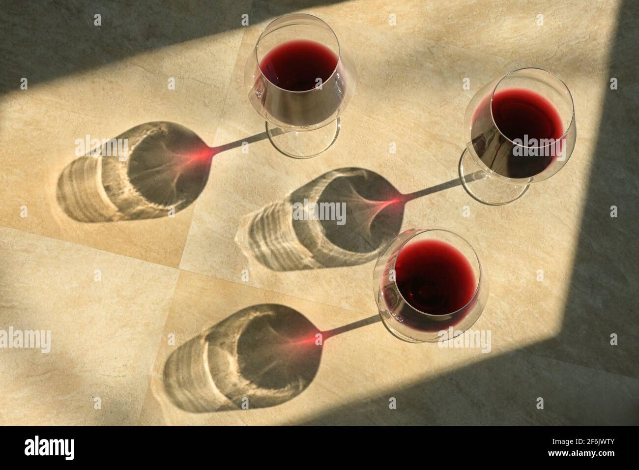 Drei Gläser Rotwein und Schatten auf dem Steintisch Stockfoto