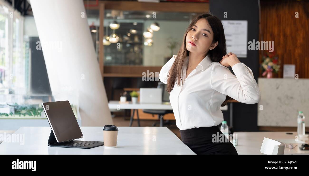 Porträt einer Geschäftsfrauin, die sich ausruhen kann, während sie sich am Tisch in der Wohnung befindet. Job- und Freizeitkonzept. Stockfoto